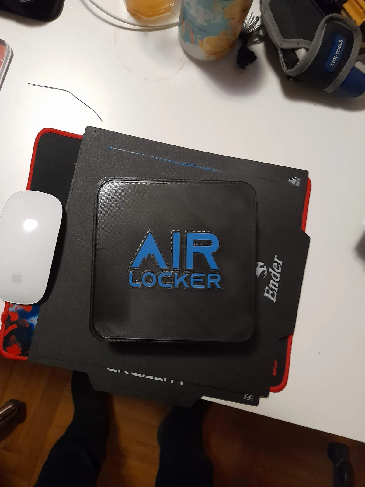 A printed AIR LOCKER lid with the blue logo, still on the magnetic build plate of a Creality Ender printer