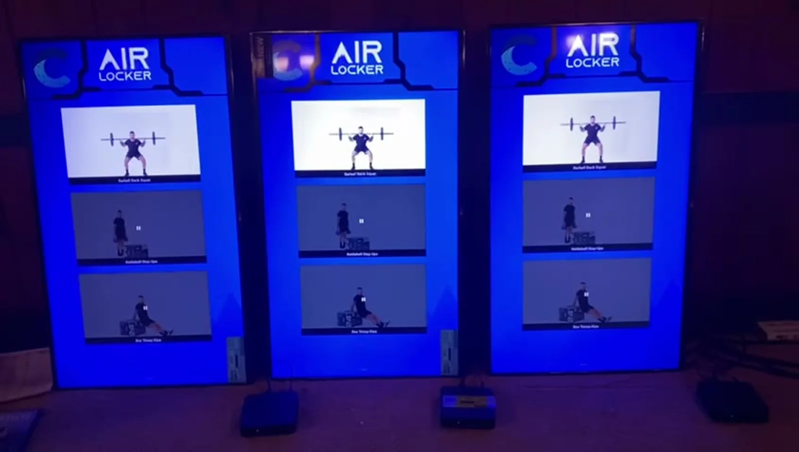 Three portrait screens in a studio showing the same three exercise clips, with one AIR LOCKER unit on the floor beneath each screen