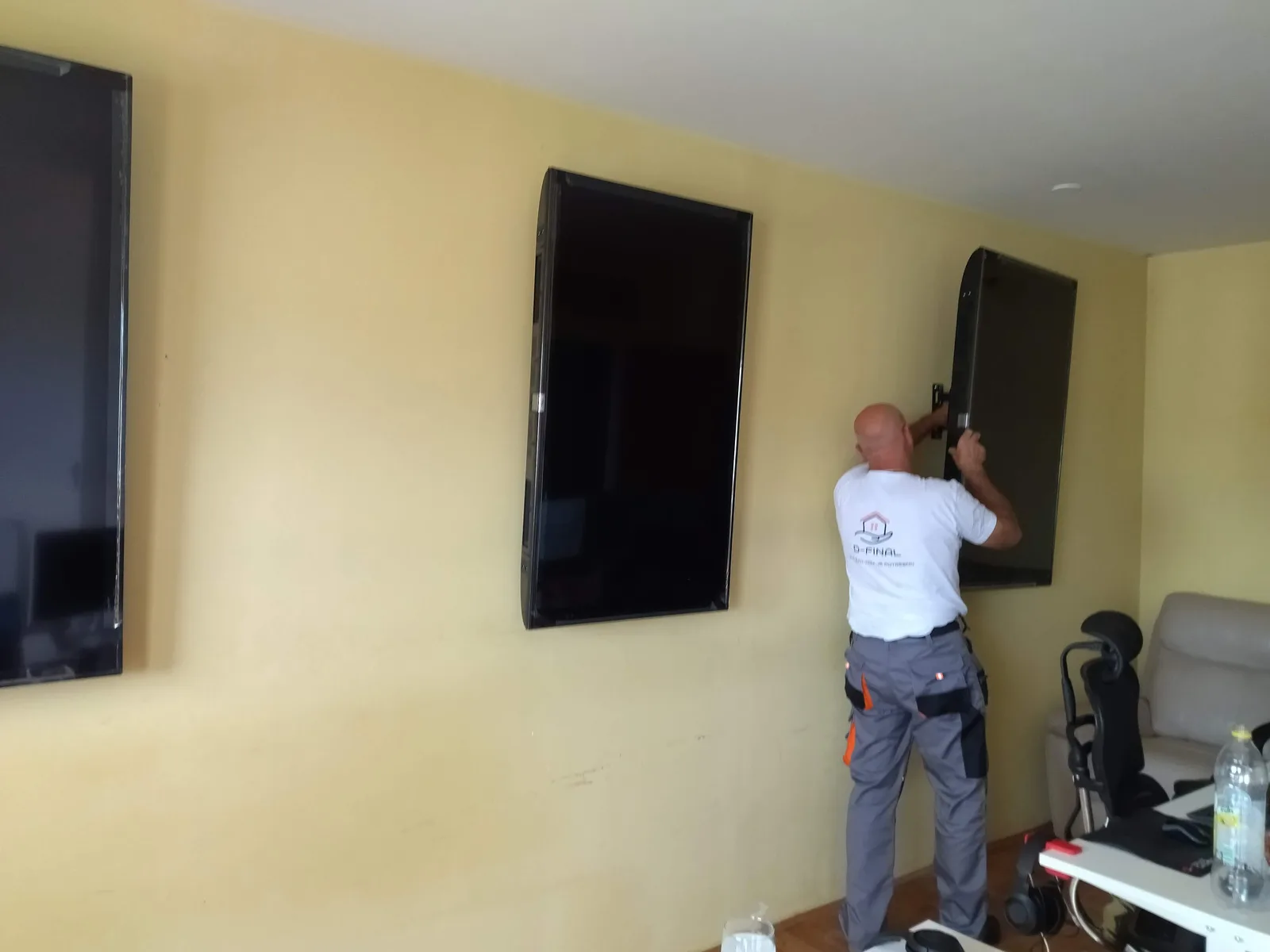 A contractor mounting a large panel onto a wall bracket